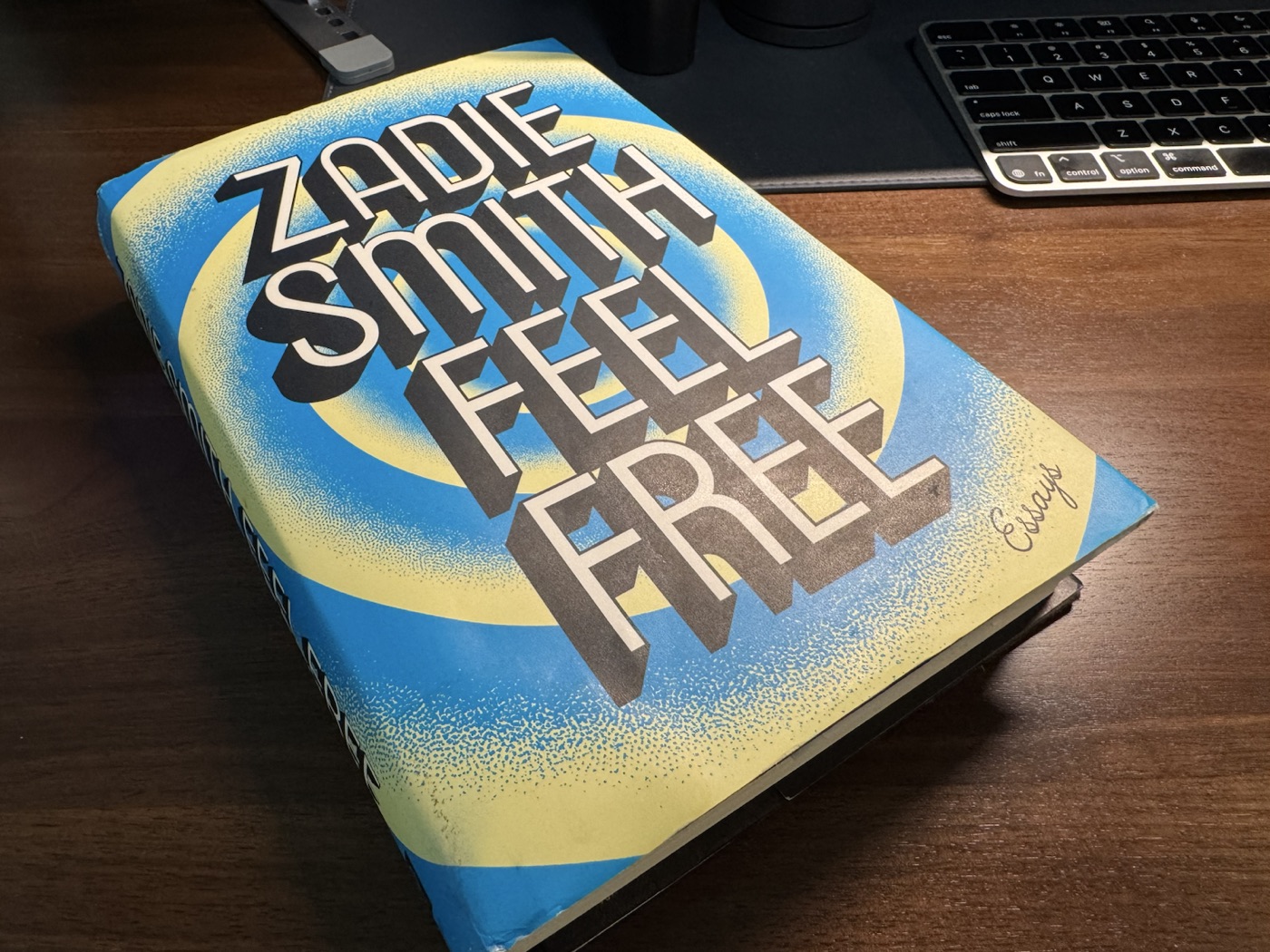 Zadie Smith's Feel Free on a wooden desk beside a keyboard.
